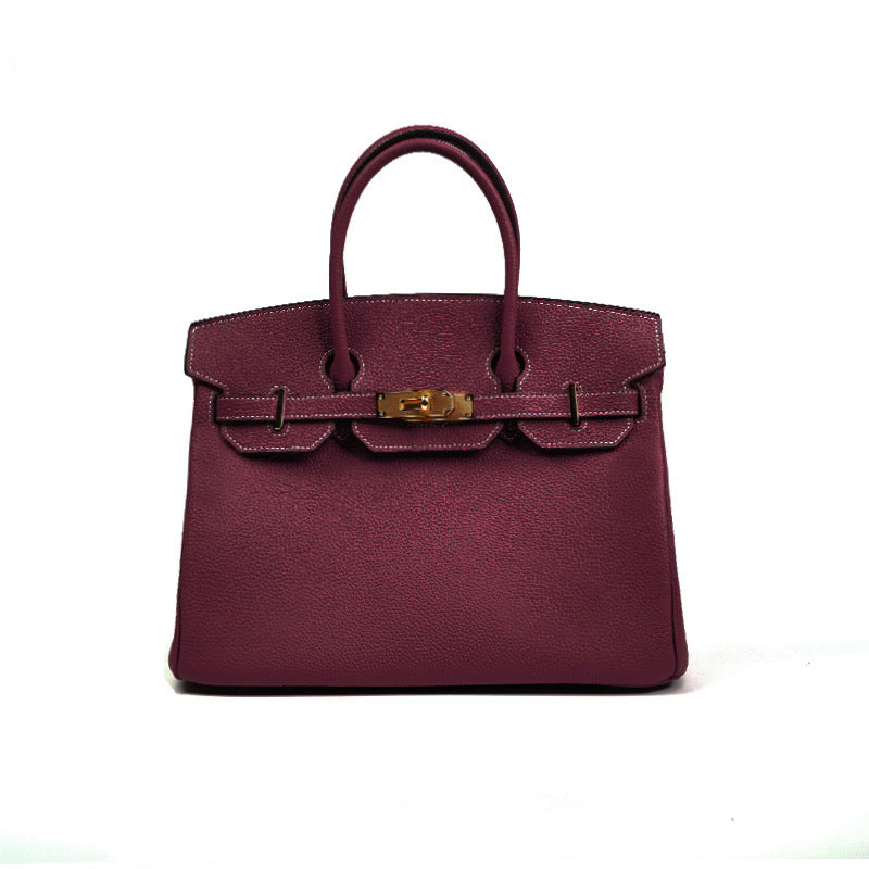 Maroon handbag with gold hardware on a white background